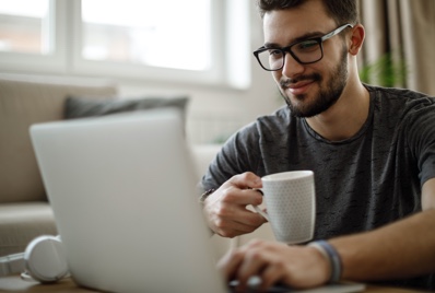 Man using a computer while drinking coffee.